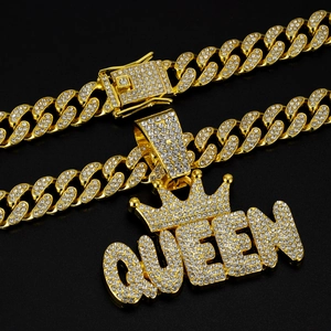 Macro shot of gold Cuban link chain with iced out QUEEN pendant and crown detail
