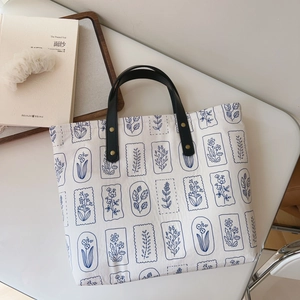 Minimalist canvas tote bag with blue botanical stamp print and black leather handles