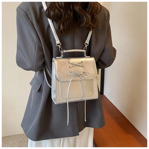 Detail view of silver metallic square backpack with bow lacing and top metal handle