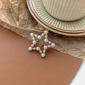 Macro view of a star-shaped pearl hair clip with gold metal base on vintage background