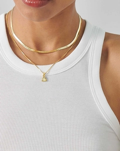 Close-up of gold snake chain and box chain necklace with triangle birthstone pendant