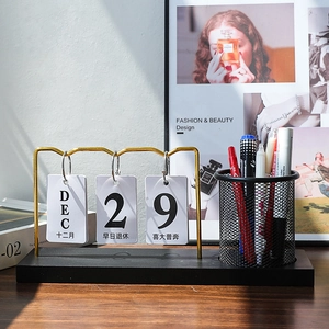 Minimalist desk calendar with pen holder and gold metal frame on a black wood base