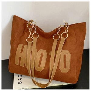 Detailed shot of a brown tote bag featuring HOTO lettering and a mixed chain strap