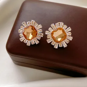Boucles d'oreilles vintage dorées avec zircon ambre sur boîte à bijoux en cuir brun