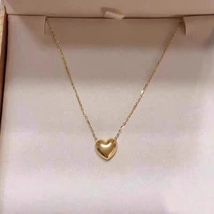 Close-up of 18K gold 3D heart pendant on fine chain in a pink jewelry gift box