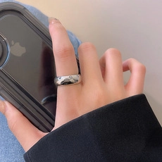 Close-up of polished silver wide band ring with delicate star engravings on finger