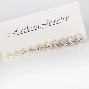 Set of 9 pairs of gold teardrop zircon stud earrings displayed on a white fashion jewelry card