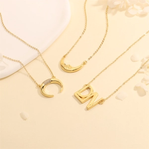 Detailed shot of 18k gold plated necklaces featuring crescent moon and letter pendants