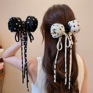 Detailed view of polka dot bow hair claw with long ribbon tassels and silk fabric texture
