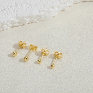 Polished 14K gold plated ball stud earrings with butterfly backs on minimalist stone background