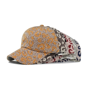 Close-up of stacked leopard print cotton baseball caps with 100% cotton tag detail