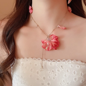 Detail of pink fabric flower pendant necklace with crystal beads on a golden chain