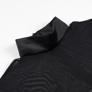 Détail d'un haut noir chic à col montant en mesh transparent et finitions en satin doux