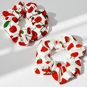 Détails de chouchous en satin avec imprimés fraises et cerises sous une lumière douce