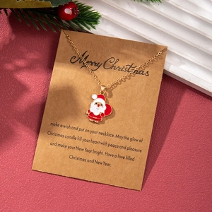 Close-up of golden Santa Claus enamel pendant necklace on Merry Christmas greeting card