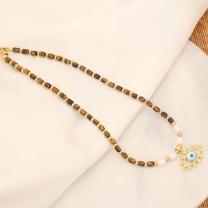 Evil eye natural stone necklace with gold beads and white pearls on fabric