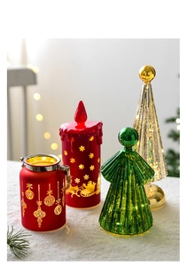 Close-up of LED Christmas candle and glass tree ornaments on white artificial snow