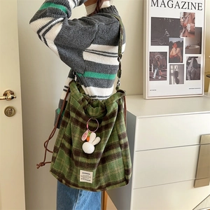 Detail of wool plaid drawstring bag with a cute white bunny charm and pink tag