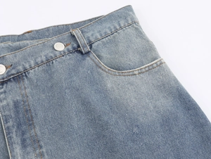 Detail of washed blue denim skirt waist with silver metal button and double stitching