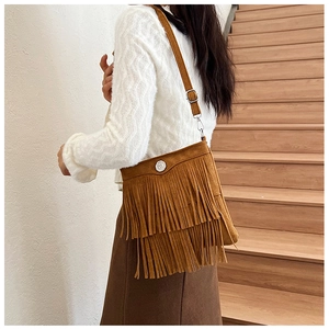 Brown tassel crossbody bag in suede texture styled with white sweater and brown skirt