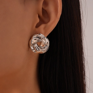 Close-up of large silver knot stud earring with polished metallic finish on a model
