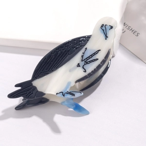 Detail of bird-shaped acetate hair claw clip featuring black and translucent white body