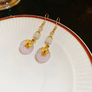Vue macro de boucles d'oreilles pompons avec donut en calcédoine rose et motifs nuages