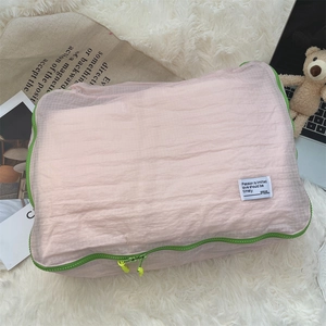 Detail of pink mesh travel organizer with neon green zipper on soft plush background