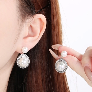 Détail de boucles d'oreilles perles argentées avec halo de cristaux sur modèle