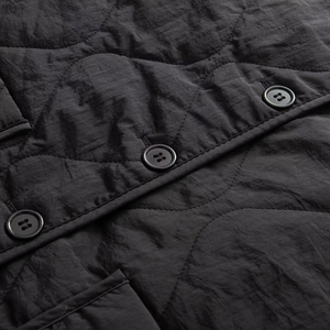Close-up of black quilted vest featuring wave patterns and classic four-hole buttons