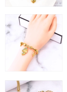 Close-up of gold chain bracelet with Hamsa charms and blue enamel on a model wrist