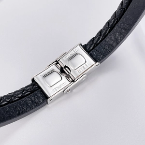 Gros plan sur le fermoir en acier inoxydable d'un bracelet en cuir tressé noir