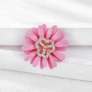 Detailed close-up of pink daisy brooch with gold clover center and sparkling rhinestones