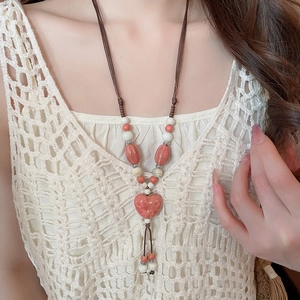 Détail du collier cœur en céramique rose avec cordon sur le haut en dentelle du modèle