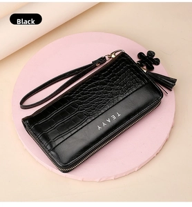 Detail of black long wallet with crocodile embossing, floral tassel and wrist strap