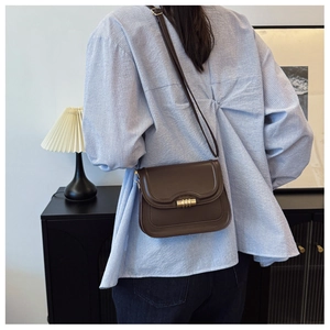 Detailed view of dark brown vintage leather crossbody bag with gold metallic lock closure