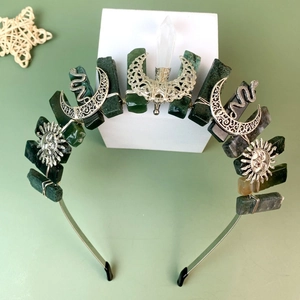 Celestial crystal crown with silver moon, sun, and snake accents on a white base