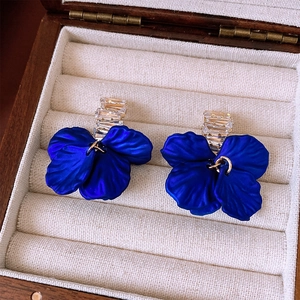 Macro shot of blue flower earrings with zircon crystals in a luxury wooden box