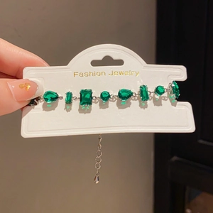 Close-up of french luxury silver bracelet with mixed-cut green gemstones and extender chain