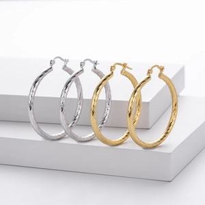 Detail of twisted S925 sterling silver hoop earrings in gold and silver finish