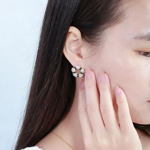 Close-up of elegant flower stud earrings with black and white rhinestones on model