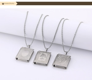 Detail showing various engraved book-shaped stainless steel locket pendants on thin chains