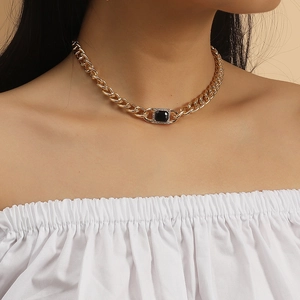 Detail of chunky gold Cuban link necklace with large black square gemstone on neck