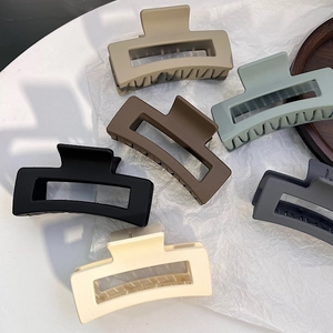 Detail of six matte rectangular hair claws in Morandi colors on textured paper background