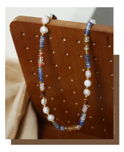 Detail of bohemian pearl and natural stone beaded necklace on a rustic wooden backdrop