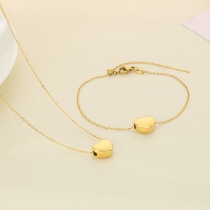 Gros plan sur l'ensemble collier et bracelet cœur en acier inoxydable plaqué or 18 carats