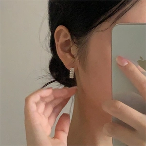 Detail of 925 sterling silver hoop earring with rectangular zircons on ear