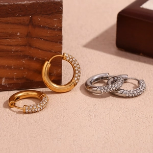 Dettaglio di orecchini a cerchio in oro e argento con pavé di zirconi scintillanti