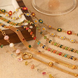 Detailansicht bunter Emaille-Gänseblümchen und goldener Herz-Armbänder auf Holzbox
