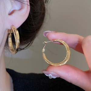 Detailed close-up showing gold double-hoop earring design and secure spring clasp mechanism